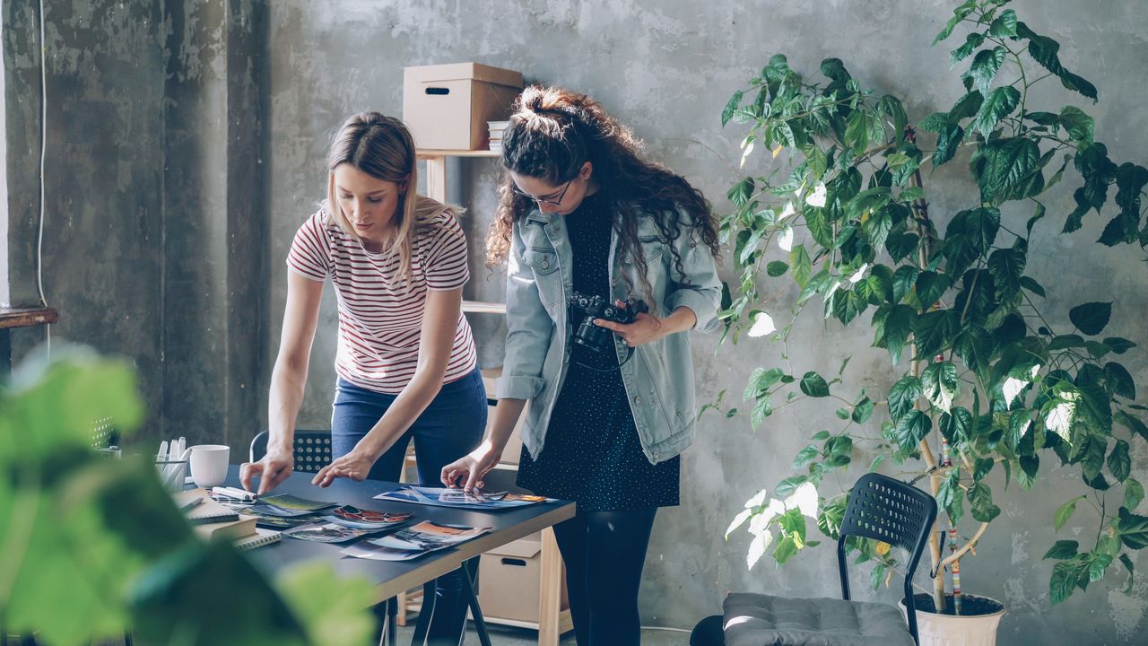 Deux créatrices examinent des photographies dans un bureau moderne.