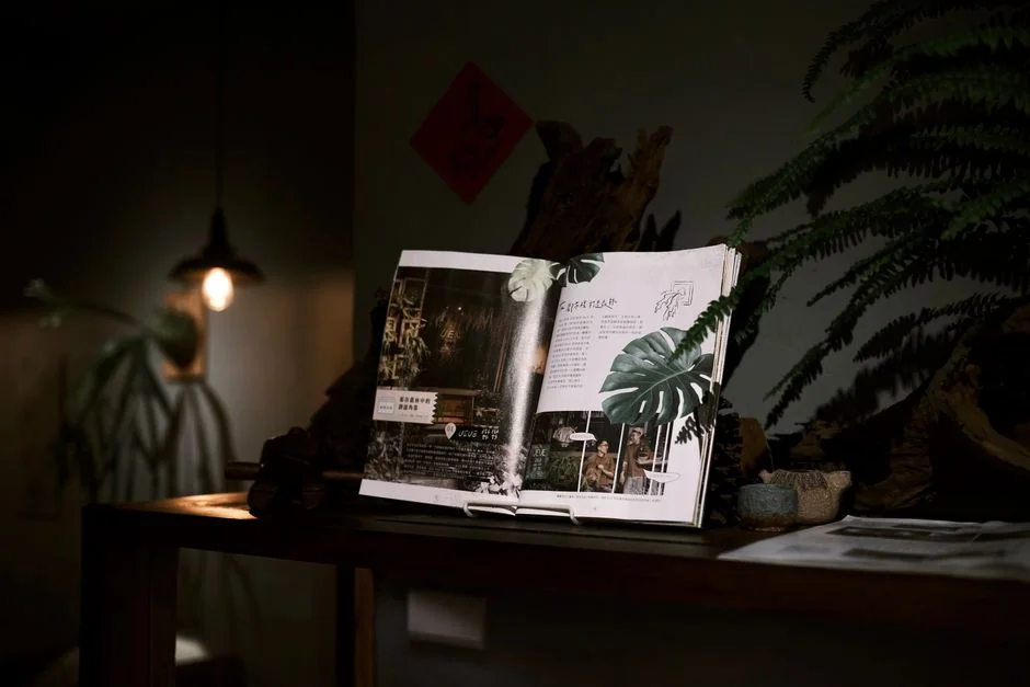 A man sits on a sofa reviewing his art portfolio filled with various illustrations.
